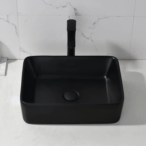 Black ceramic rectangular vessel sink with faucet and drain, contrasting on white counter, modern design for bathrooms