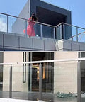 Solid 304 Stainless Steel Railing Post Kit For Decks And Staircases supporting glass panels on a modern balcony with a person. 