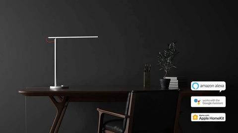 Lit Smart LED Desk Lamp With Remote Control on dark desk, compatible with Alexa, Google Assistant, Apple HomeKit icons shown.
