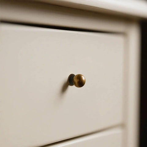 Built Like A Tank Solid Zinc Alloy Cabinet Knobs 10 Pack Antique Brass single hole ball knob on white drawer.
