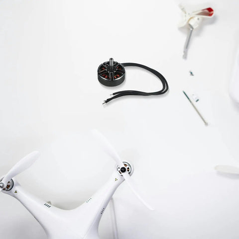 Brushless Alloy Drone Motor 1300KV For 7 Inch Drones placed on a white table with drone parts, compact electric motor for DIY UAV setup.
