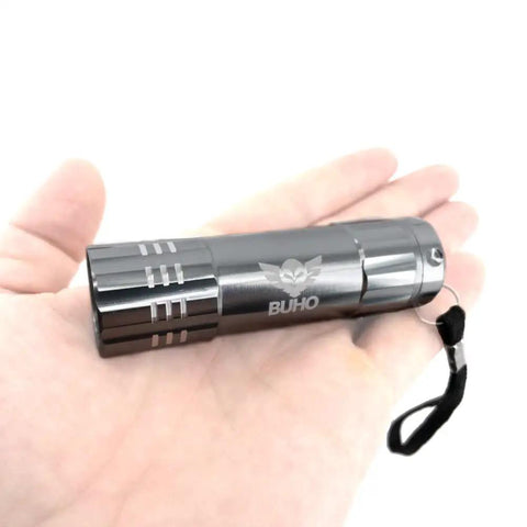 Close-up of a metallic pocket flashlight from the Cordless 4 Inch Clamp Fan Kit With 18V Ryobi Battery, shown resting in a hand.