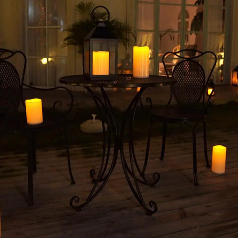 Outdoor Waterproof Flameless LED Pillar Candles Set 6 8 10 Inch With Remote And Timer Battery Operated Weatherproof Plastic Candles In Ivory White lighting up a patio table and chairs at night