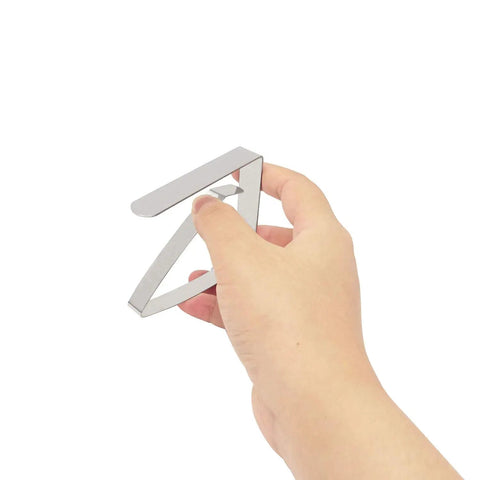 Hand holding heavy duty stainless steel tablecloth clip from the Heavy Duty Stainless Steel Tablecloth Clips Set Of 6 For Outdoor And Indoor Use Beefy Large Table Cover Clamps Holds Tablecloth Securely Up To 2 Inches Thick Durable Clamp Holders.