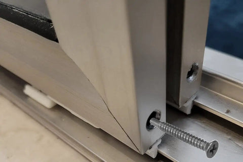 Close-up of Top Shelf Stainless Steel Screws For Framed Shower Door Panel Assembly, Pack Of Four, One Point Three Eight Inches installed into aluminum frame.