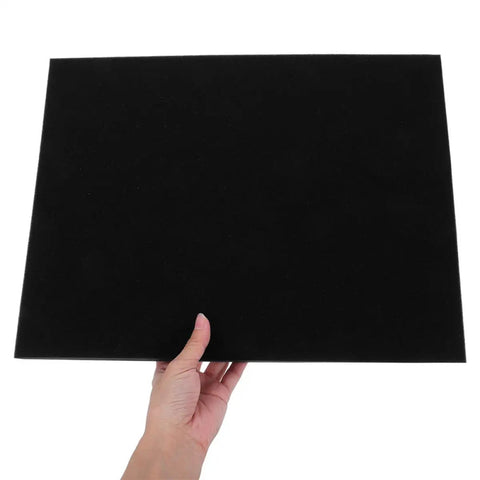 Person holding a 4 Pack Black Hard Foam Blocks 405x305x25mm Shipping Padding Sheets For Packaging Protection Cushioning Inserts.