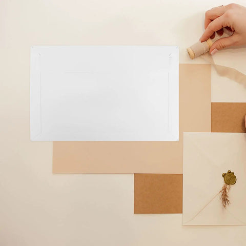 Rigid Self Seal Mailers 90 Pack White Cardboard Envelopes shown with hand holding twine, decorative envelope on beige background