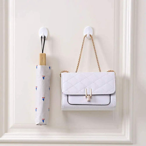 Heavy Duty Adhesive Wall Hooks For Bathroom And Kitchen Built Tough With Super Grip Oil Resistant Plastic Surface Mounts Zero Hole Punch Needed Fully Waterproof Set Of Three White Units holding a white handbag and umbrella.