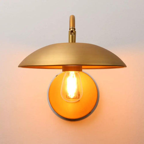 Dope Industrial Swing Arm Wall Sconce In Brass Finish Adjustable Hardwired Wall Lamp With Metal Base Retro Indoor Lighting Fixture For Hallway Bedroom Living Room Dining Area And Cafe Decor showing lit bulb beneath brass UFO-shaped shade and round metal base.