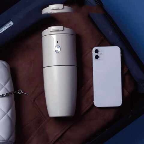 Portable Mini Coffee Machine With Automatic Bean Grinder And Quick Brewing For Smooth Espresso At Home Or On The Road next to a phone