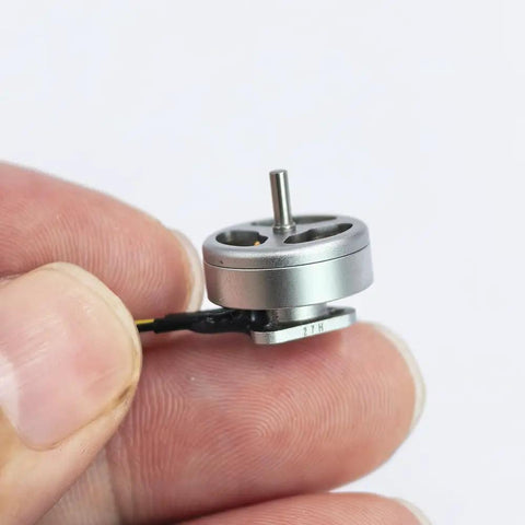 Close-up of 1103 Beefy High Speed Brushless Motor 15000KV for RC Drones held between fingers, silver outer rotor design