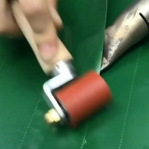 Close-up of red 40mm silicone seam roller with brass detail on green roofing membrane