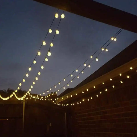 Solar Powered Outdoor String Lights 50 LED 24ft 8 Modes Waterproof Fairy Lights With Globe Crystal Balls illuminating a backyard