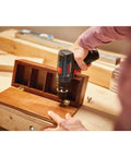 Person using Ultra Compact 12V Max Hammer Drill And Driver Kit with 3/8 Inch Auto Chuck on wooden box, ideal for tight spaces.