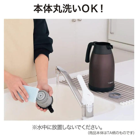 Stainless Steel Vacuum Carafe 1.9 L with One-Touch Pour being washed in a kitchen, showing brown tank-grade build and screw-off lid.