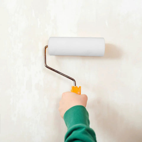 Top Pro Level Paint Roller Brush Head With Padded Handle For Zero Sweat Wall Covering And Sharp Trim Work A True Home Reno Game Changer For Swift Finish Efforts held by hand on wall.