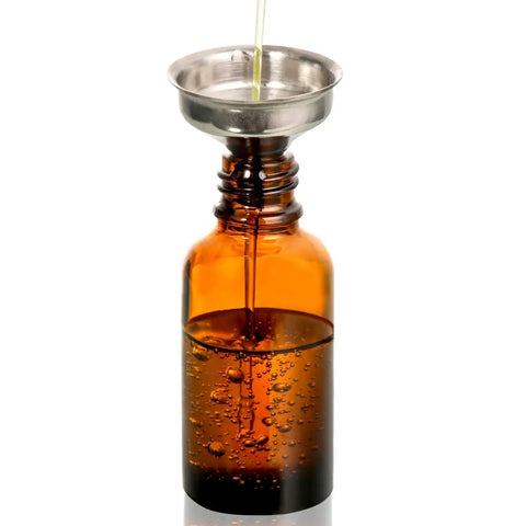 Twelve Knockout Amber Glass Dropper Bottles With Three Slick Stainless Steel Funnels And One Long Graduated Pipette Plus Twenty Four Waterproof Labels For Essential Oils And Hassle Free Beauty Blends pouring oil into a bottle using a funnel.