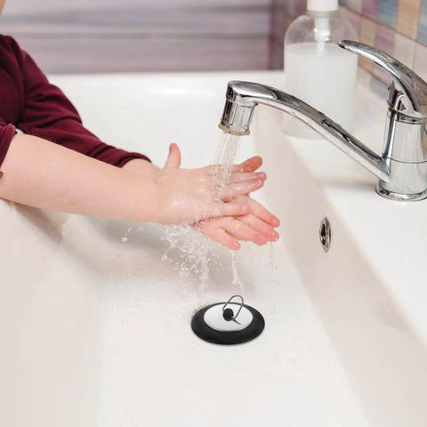 Stainless Steel Seal Rubber Bathtub Drain Plug for Bathrooms in use, with water running over hands in a modern bathtub.