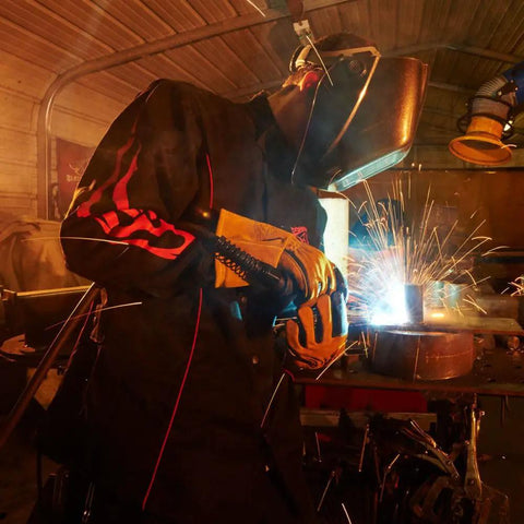Welder wearing Black Flame Accent Welding Jacket 9 Oz Flame Resistant Cotton XL with Red Flames Trim and sparks flying