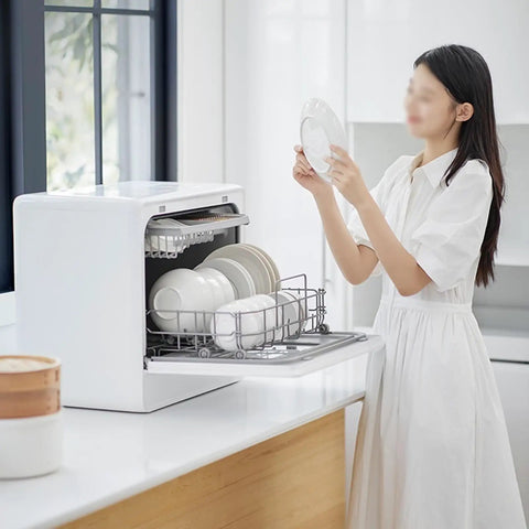 Woman loading plates into Flat Out Reliable Compact Countertop Dishwasher With Fully Automatic Smart Drying And Triple Wash Filter For Tiny Kitchens Or Rv Campers No Sweat Setup Easy Glide Rack Holds Massive Dinner Plates Built Different Quality.