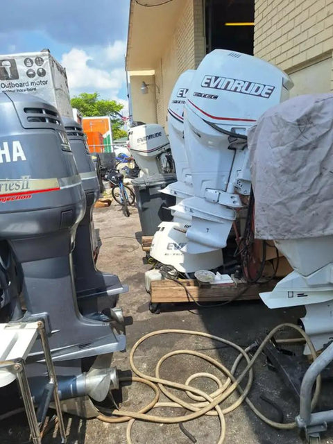 Outboard motors in a storage area, including multiple Evinrude and Yamaha models, alongside marine equipment and hoses.
