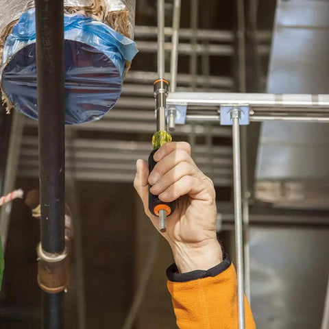 Person using Heavy Duty Magnetic Nut Driver Set 6-Inch with color-coded grips and hollow shaft for long threads in industrial setting.