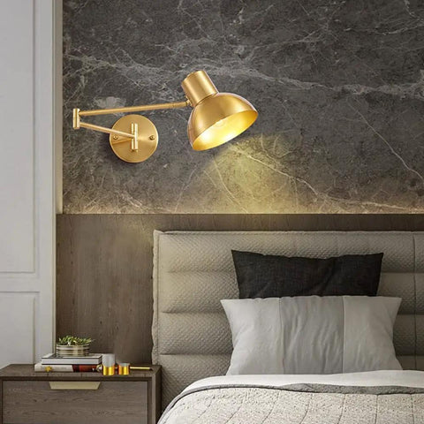 Badass Industrial Metal Swing Arm Wall Sconce With Rock Solid Adjustable Dome Shade And E27 Socket Hella Sturdy For Bedroom Reading Vibes And Slick Black Brass Finish Modern Wall Lamp angled view with gold finish in bedroom setting.