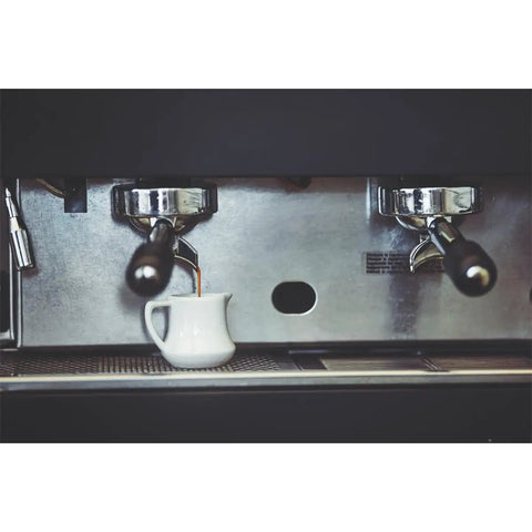 Close-up of espresso machine brewing coffee into a cup, demonstrating use of Decalcifier Descaler Solution for Espresso Machines, 250ml Pack of 2 Bottles.