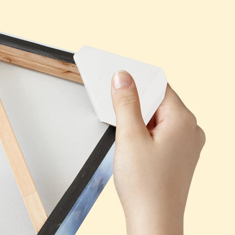 Hand placing a Super Tough Adjustable Cardboard Corner Protector on a picture frame for secure moving and artwork protection.