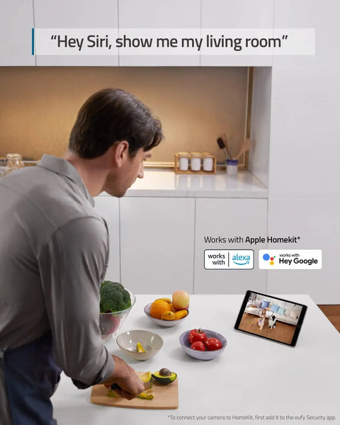 Person using voice assistant with tablet displaying Two Camera Indoor Security Kit With 2K Pan And Tilt Plug In Wi Fi Camera.