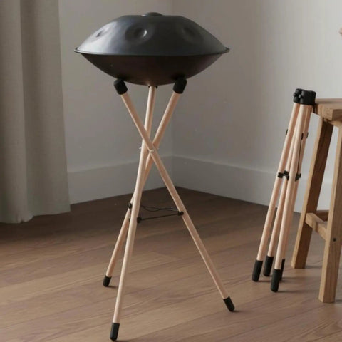 Heavy Duty Beech Wood Drum Rack With Tripod Legs And Adjustable Rope Mount For Steel Drums Folds Flat For Tour Ready Travel Hella Stable Pro Vibe With Thick Sponge Padding Large on tripod in room.