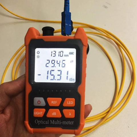 Front view of orange handheld optical power meter with yellow fiber lead and blue FC/SC/ST connector, 1310 nm display.