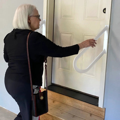 Person using Outdoor Stair Handrails Rock Solid Wall Mount With White Powder Coat Finish for safety support at garage door.