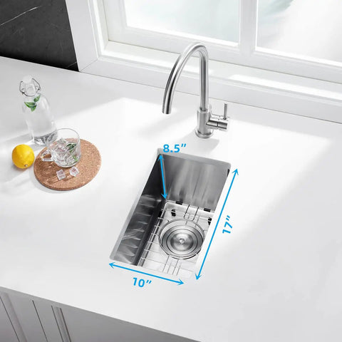 Stainless Steel Single Bowl Bar Sink For Undermount Prep In Small Kitchens 10 Inch By 17 Inch 8.5 Inch Deep 16 Gauge Includes Sink Strainer Waste Basket And Bottom Grid Scratch And Stain Resistant installed under a white countertop near a window.