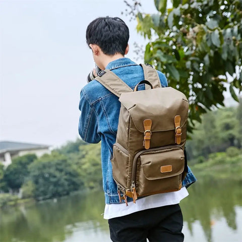 Person wearing Chic Canvas Camera Backpack for outdoor photography near a lake, showcasing large capacity and tripod holder