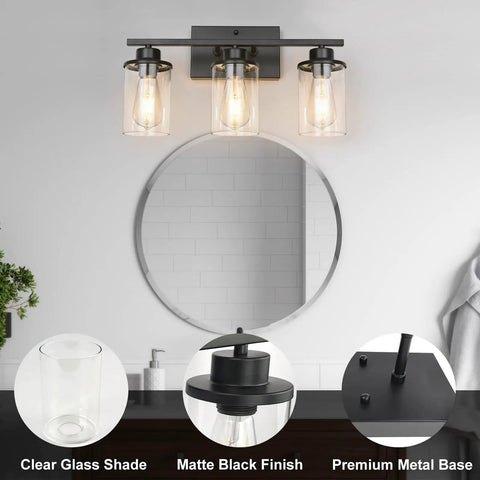 Slick Black 3 Light Vanity Light Fixtures Over Mirror With Clear Glass Shades in bathroom setting, round mirror reflection.