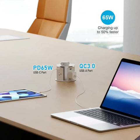 Slick Flush Mount Pop Up Socket Drops Straight Into Countertops Featuring Qi2 Magnetic Wireless Charger With 65W Fast Charging Double Usb Ports Zero Hassle Setup In Fresh White on a desk with tablet and laptop.
