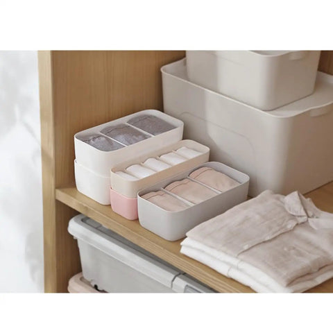 Slick Four Compartment Plastic Underwear Storage Box For Closet Dresser Drawers neatly organizing bras and leggings in a tidy closet.