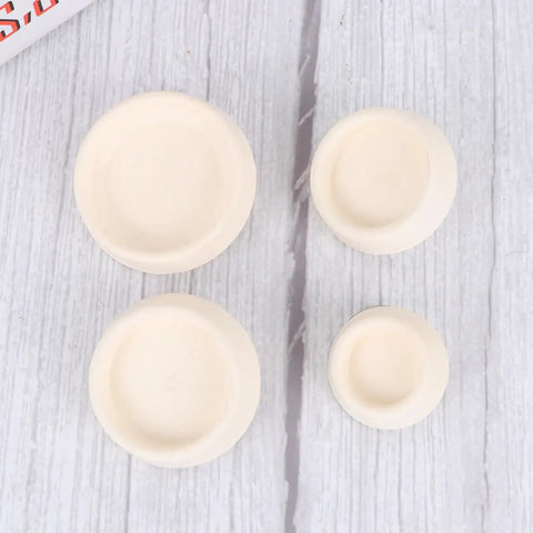 4pcs White Rubber Bathtub Stopper with Hanging Ring for Sink Drains in assorted sizes on a wood surface.