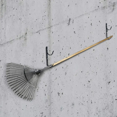 Two Pack Heavy Duty Black Aluminum Pool Pole Hangers With Screws holding garden rake on concrete wall