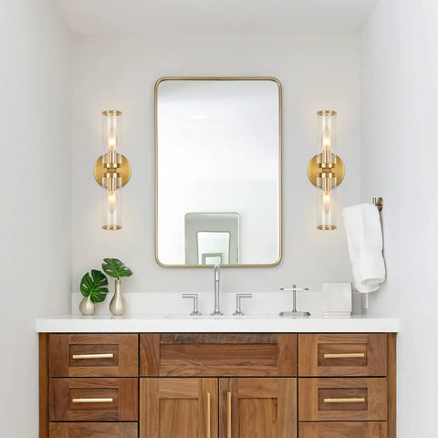 Bathroom view with Gold Wall Sconce Lights Two Pack With Candle Shaped Glass Shades flanking a mirror on wooden vanity.