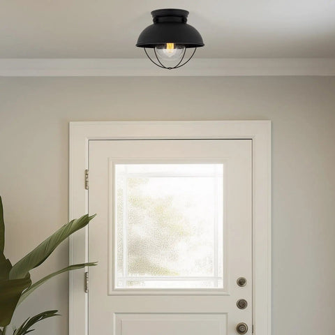 Farmhouse Nautical Flush Mount Ceiling Light With Seeded Glass Shade In Matte Black Finish, placed in foyer above white door.