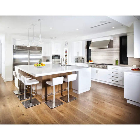 Modern kitchen with white cabinetry, stainless steel appliances, and a large island with bar stools, showcasing LED recessed lighting.