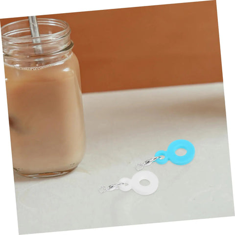 Six Piece Set Straw Charms For Tumblers And Cups Cute Dangle Toppers next to a glass cup on a table.