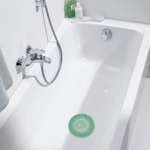 Banish Clogged Drains Fast With This Flexible Drain Strainer Set in a white bathtub with a green rubber strainer.