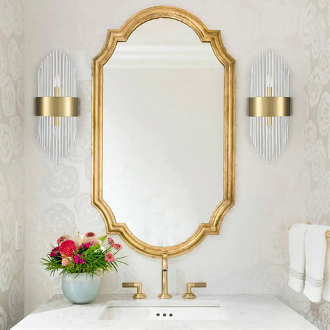 Mid Century Brass Wall Sconce With Glass Rods 2 Pack next to a gold-framed mirror in a bathroom