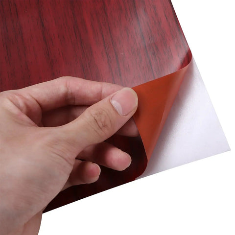 Brown Wood Grain Peel And Stick Wallpaper For Furniture Makeover Self Adhesive Cabinet Cover being peeled back for easy installation.