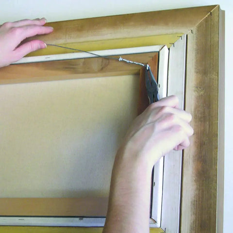 Person using 20 Gauge Galvanized Steel Wire Rope Cable 20 X 175 Feet for hanging a frame, showing hobby usage.