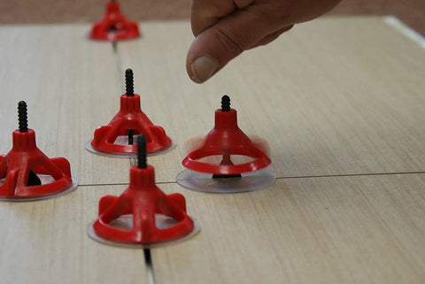 Tile Leveling System Starter Kit With 1/8 Inch Base Plates And Reusable Caps in use on floor tiles, showing spin design.