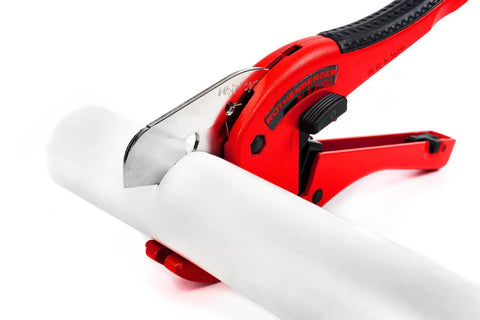Pro Grade Plastic Pipe Cutter With Stainless Steel Blade, Rubberized Handle, cutting white PVC pipe, close-up view.